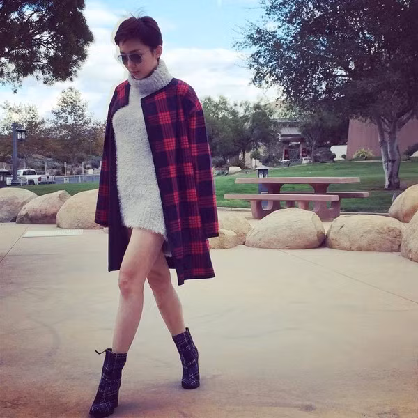 Khác với Hồ Ngọc Hà, Tóc Tiên lựa chọn phong cách cá tính với váy len xù cao cổ kết hợp cùng áo khoác kẻ đỏ và boot cao cổ họa tiết tartan. Ảnh: emdep.vn.