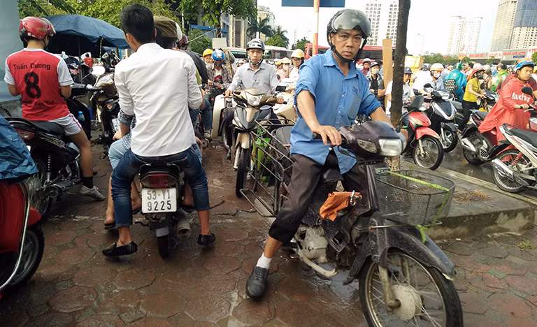 Cảnh tượng giao thông rất hỗn loạn xe máy thi nhau lao lên vỉa hè đường Dương Đình Nghệ để tìm lối đi.