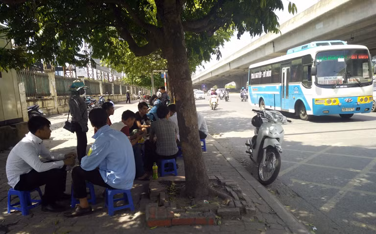 Nhiều người đàn ông còn phải trốn dưới bóng cây xanh ở ven đường, ngồi uống trà đá để tránh nắng.