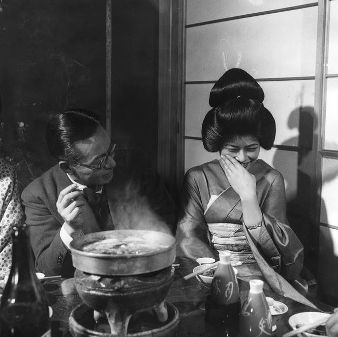 Nàng geisha cười bẽn lẽn, duyên dáng khi nói chuyện với khách vào năm 1955. Ảnh: Three Lions.