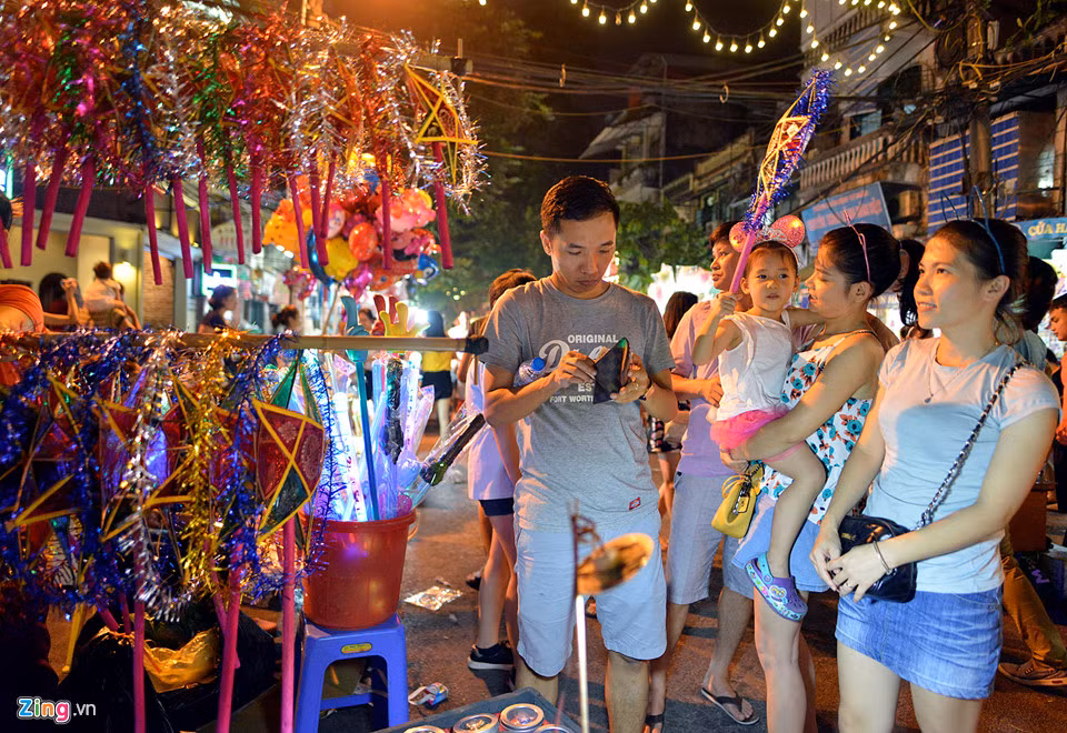 Một số gian hàng bán đồ chơi truyền thống được nhiều gia đình cho trẻ nhỏ lựa chọn. Trong ảnh, bé Bi được bố mẹ mua tặng đèn ông sao để dạo phố.