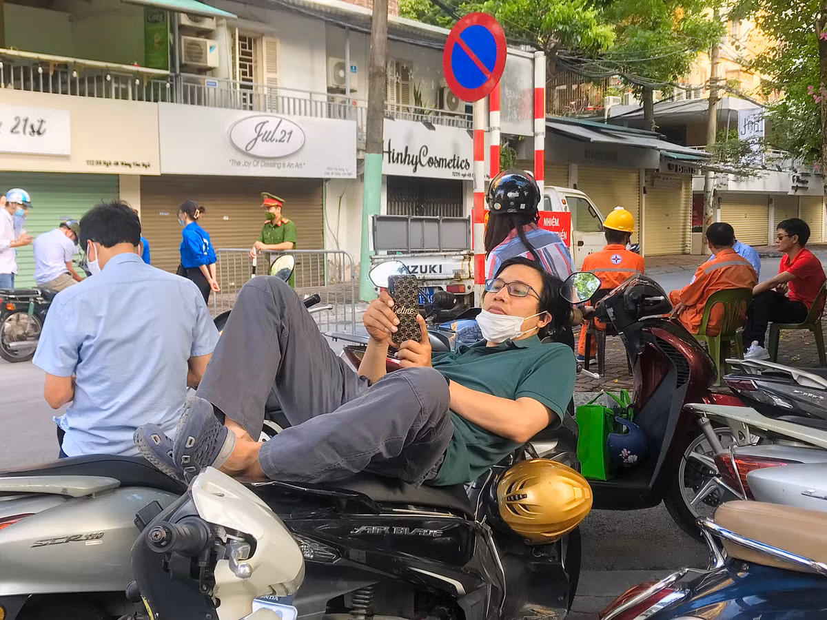 Một ông bố tranh thủ nằm nghỉ trên xe trong lúc đợi con thi xong.