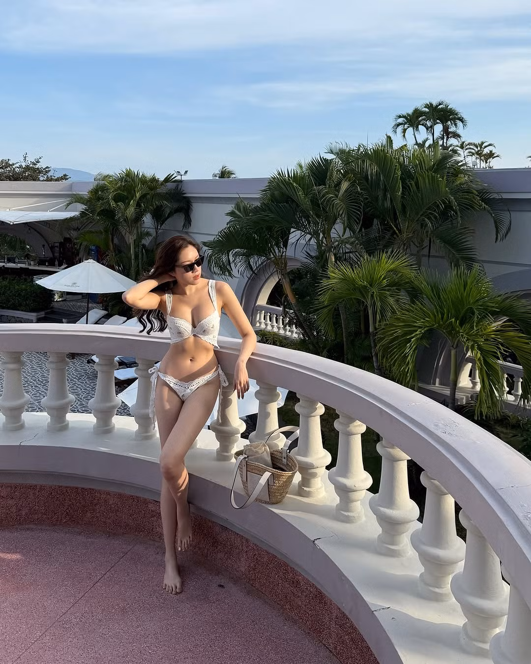 Thanh Thanh Huyền xách thêm chiếc túi cói đồng bộ với đồ bơi của nhà mốt Loewe, để tóc xoăn sóng quyến rũ.