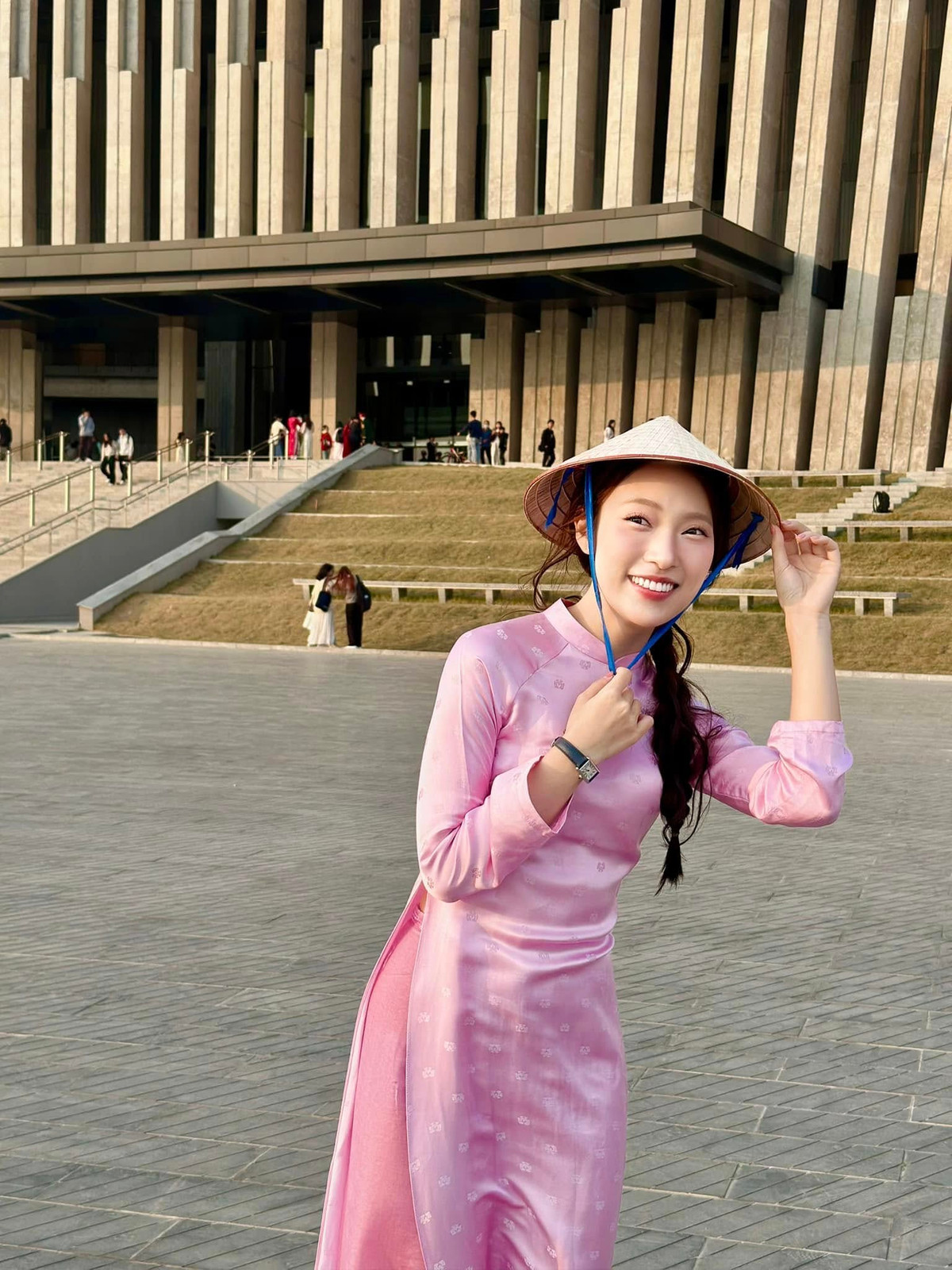 Check-in tại Bảo tàng Lịch sử Quân sự Việt Nam, cô nàng lựa chọn cho mình thiết kế áo dài màu hồng nhạt ôm nhẹ, kết hợp với nón lá truyền thống.