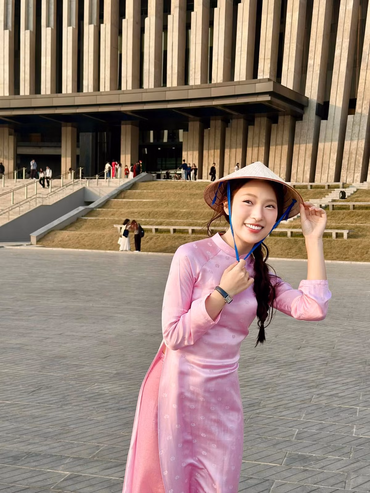 Check-in tại Bảo tàng Lịch sử Quân sự Việt Nam, cô nàng lựa chọn cho mình thiết kế áo dài màu hồng nhạt ôm nhẹ, kết hợp với nón lá truyền thống.