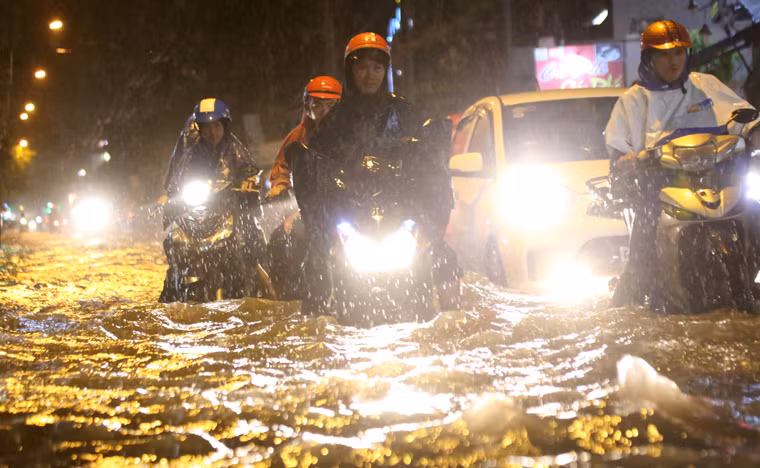 Người dân bì bõm lội qua khu vực ngập nặng để tìm đường trở về nhà trong đêm.