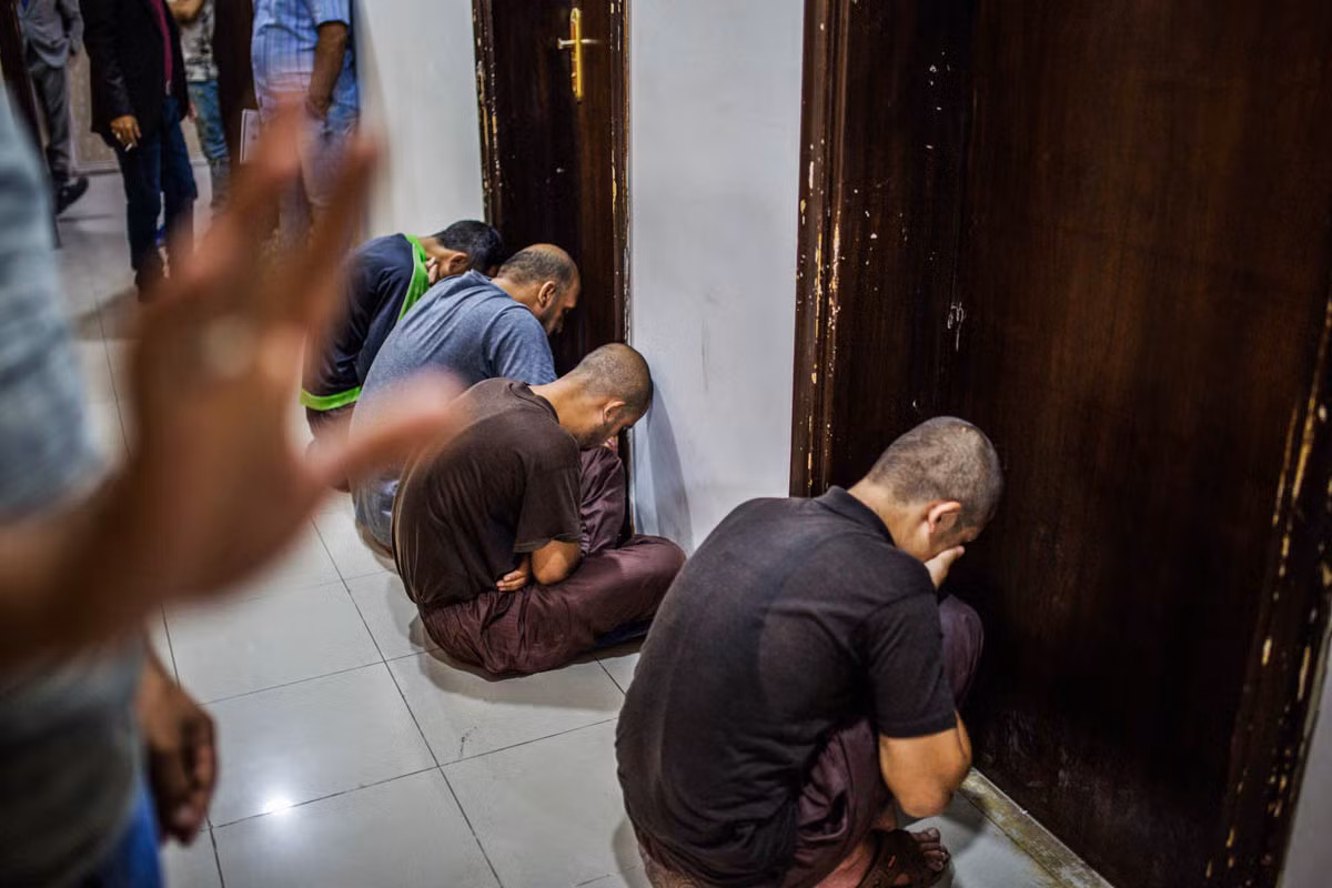 Các tù binh ngồi chờ ở hành lang trước khi vào phòng xử án tại tòa án ở Baghdad.