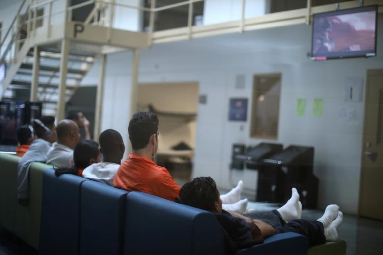 Những người nhập cư ngồi xem ti vi tại trung tâm Otay Mesa.