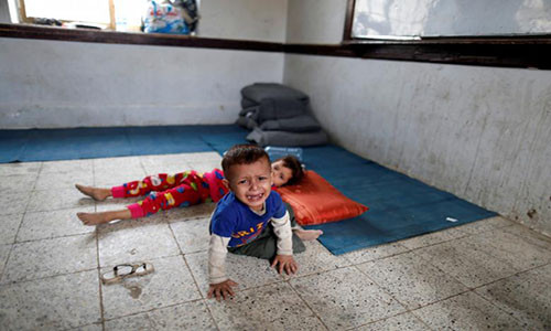 Một bé trai bật khóc khi ngồi trong phòng học của một ngôi trường được sử dụng làm nơi ở tạm bợ cho người dân Yemen sơ tán tại thủ đô Sanaa.