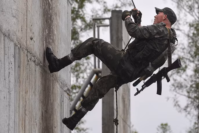 Lính trinh sát Nga mang theo vũ khí khi trèo tường vượt chướng ngại vật. Ảnh: TASS.