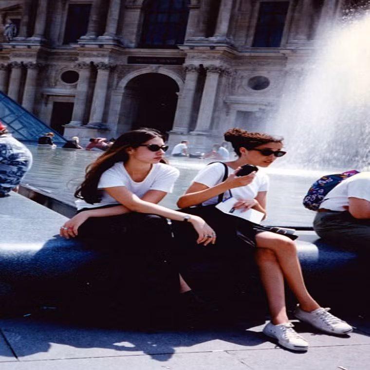 Meghan Markle, lúc 15 tuổi, trông già dặn hơn với mái tóc xoăn ngồi trước đài phun nước ở thủ đô Paris, Pháp, năm 1996.