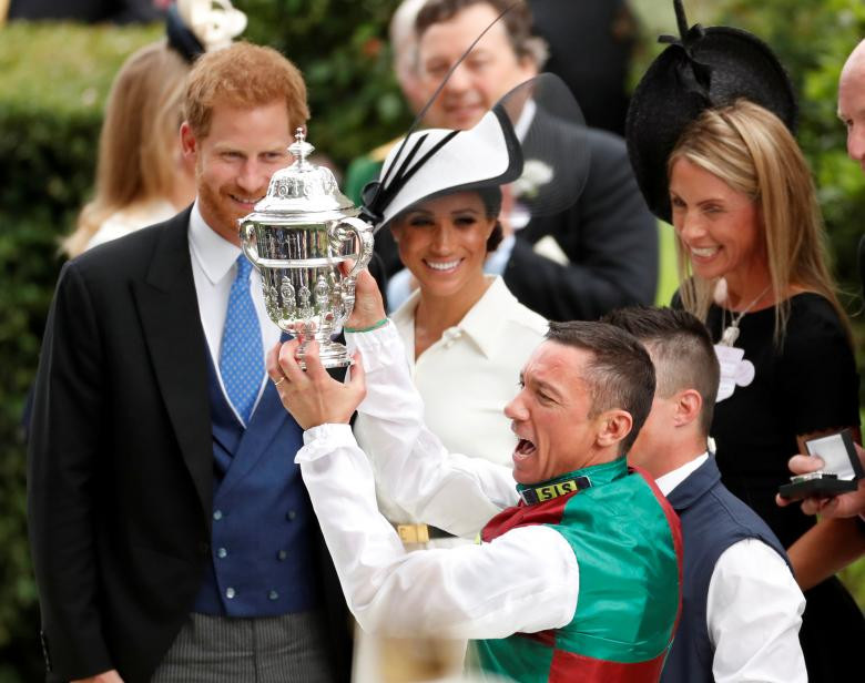 Frankie Dettori nâng cúp sau khi giành chiến thắng trong cuộc đua ngựa St James's Palace Stakes trong khi Hoàng tử Harry và Công nương Markle đứng cạnh hôm 19/6.