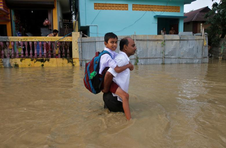 Người đàn ông cõng con trai qua khu vực ngập lụt ở ngoại ô Agartala ngày 15/6.