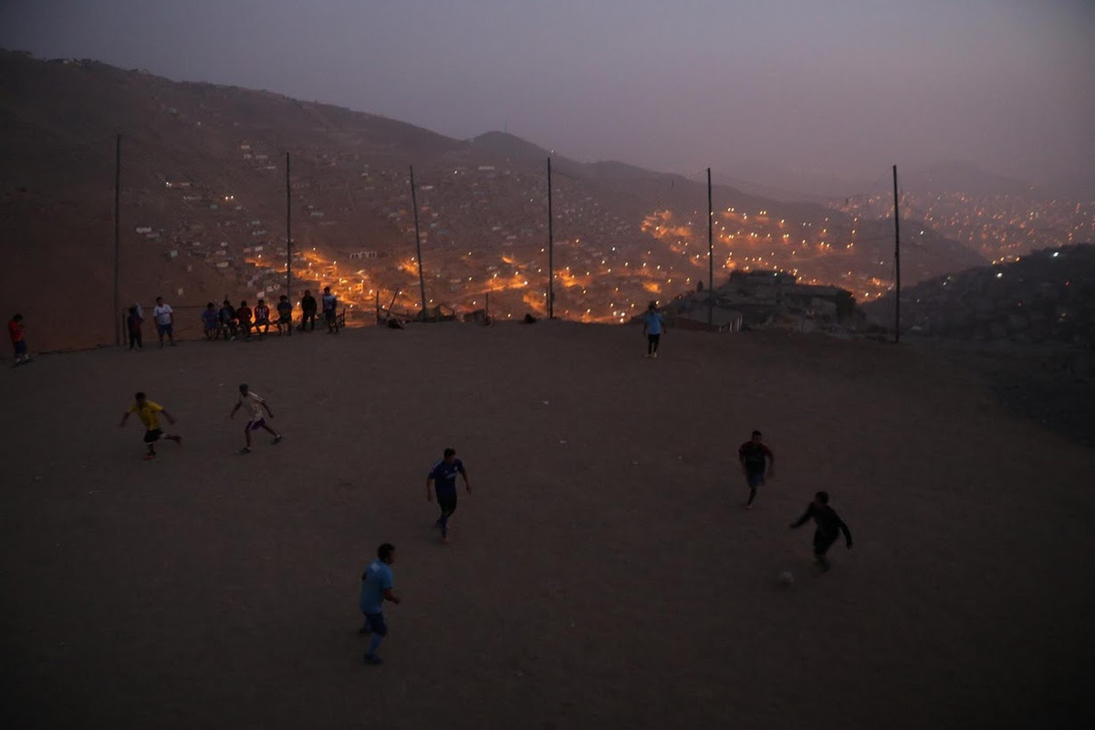 Những người đàn ông chơi đá bóng vào chiều tối tại khu ổ chuột Nueva Union.