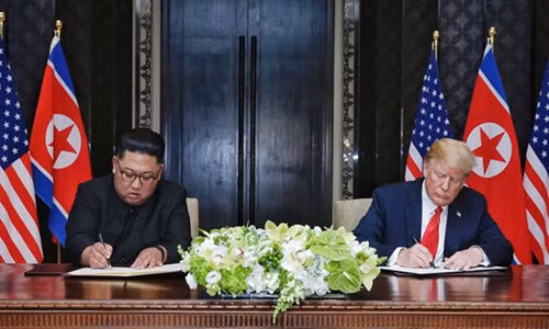 Tổng thống Trump (phải) và ông Kim Jong-un ký thỏa thuận chung ngày 12/6. Ảnh: BBC.