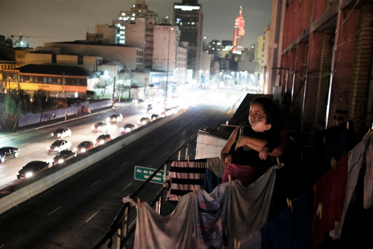 Người phụ nữ bế con gái bên ngoài ban công tòa nhà Prestes Maia.