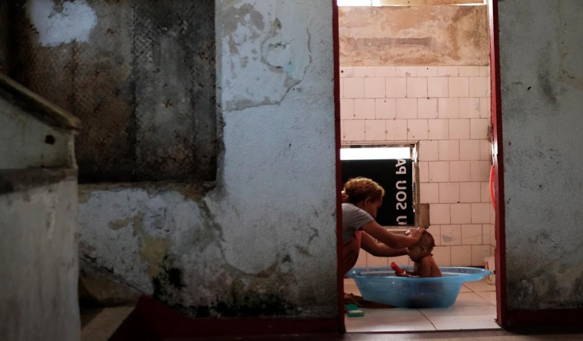 Người phụ nữ tắm cho con trong nhà tắm chung của tòa nhà bỏ hoang Prestes Maia.
