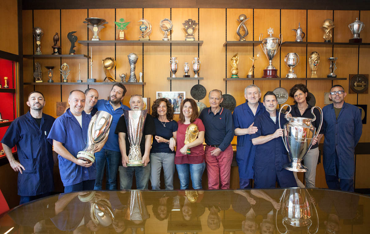 Các nhân viên của GDE Bertoni chụp hình cùng với những chiếc cúp vàng nổi tiếng do công ty này chế tạo, được trao cho đội vô địch trong các giải bóng đá UEFA Supercup, UEFA Europa League, FIFA World Cup và UEFA Champions League.