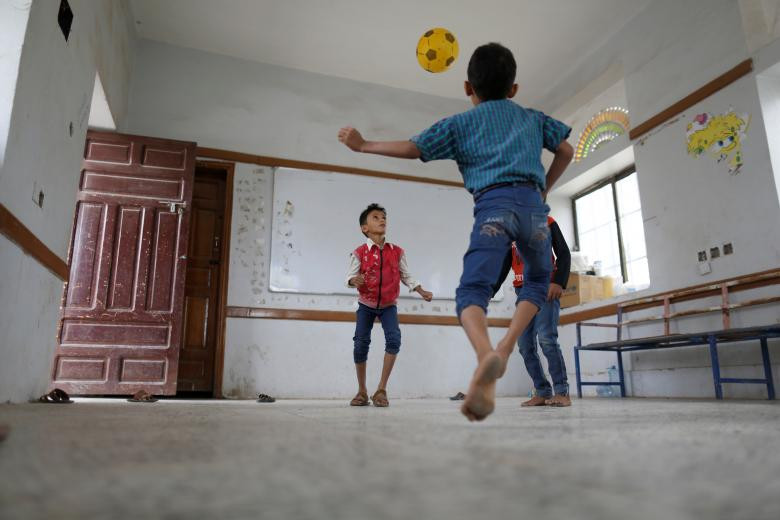 Các bé trai chơi đá bóng trong phòng học của ngôi trường được sử dụng làm trại tị nạn ở Sanaa.