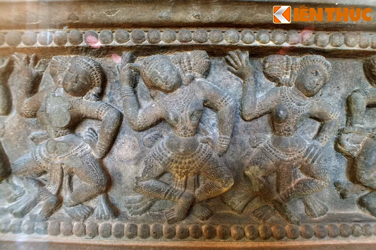 Một cạnh của bệ chạm khắc 11 nhân vật hình dáng gần giống nhau, trong tư thế múa.