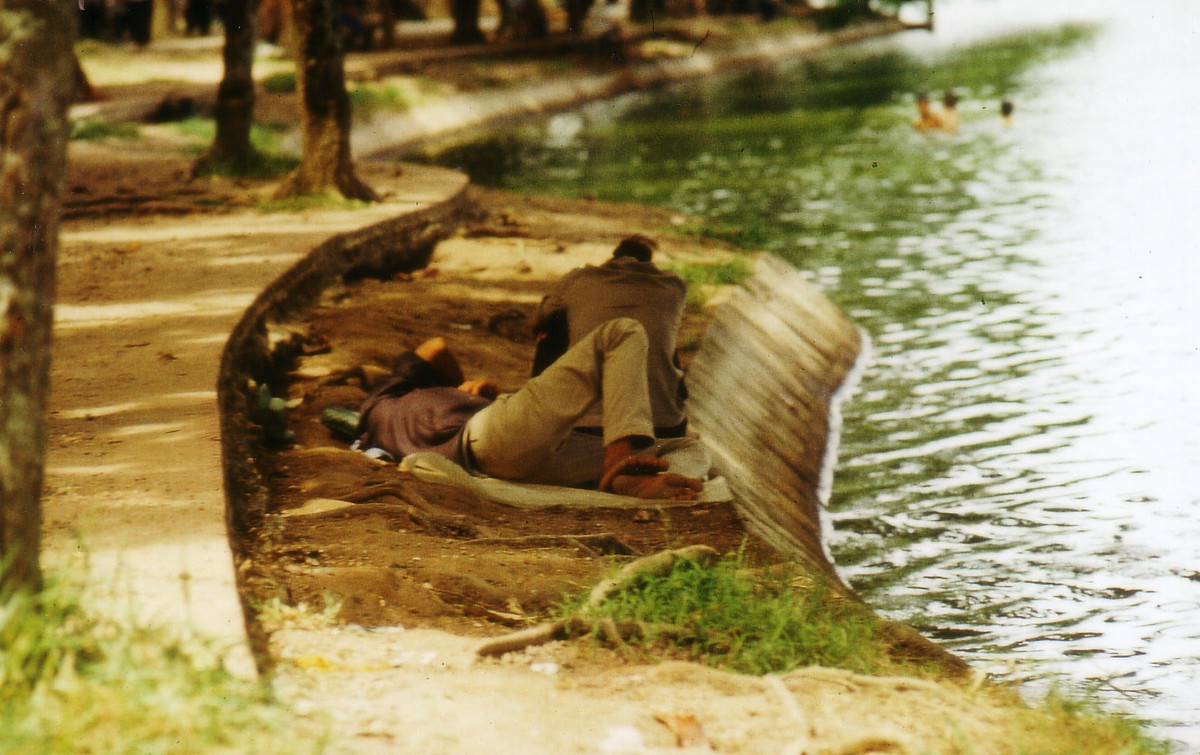 Hai người đàn ông nghỉ ngơi bên bờ hồ. Những đứa trẻ tắm dưới hồ cách đó một đoạn. Ảnh: Günter Mosle.