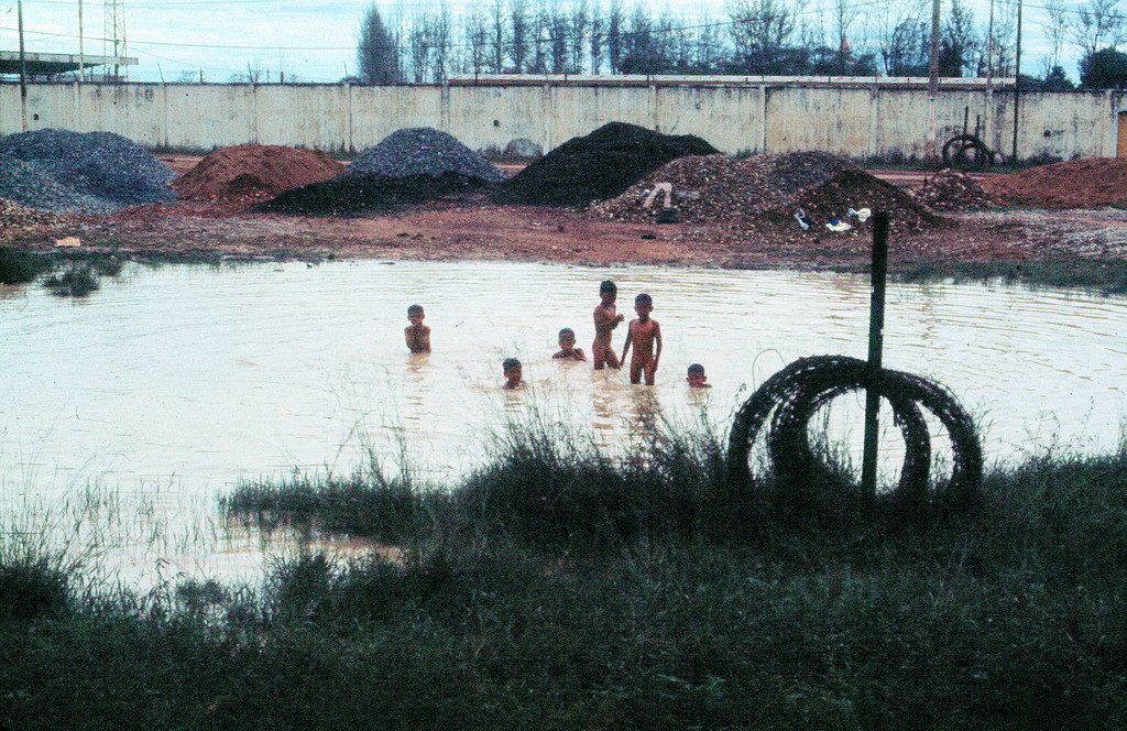 Trẻ em tắm ở vũng nước gần lối vào sân bay Tân Sơn Nhất. Khu vực này nay là công viên Hoàng Văn Thụ. Ảnh: 11thrru.org.