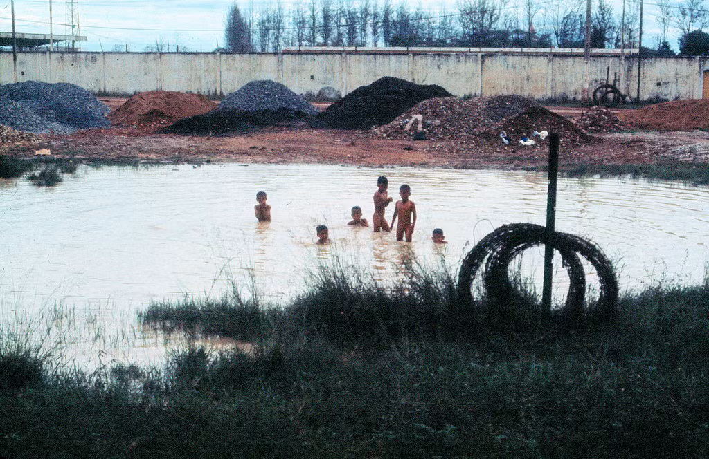 Trẻ em tắm ở vũng nước gần lối vào sân bay Tân Sơn Nhất. Khu vực này nay là công viên Hoàng Văn Thụ. Ảnh: 11thrru.org.