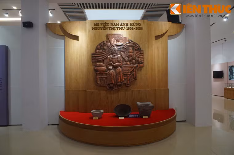 Phù điêu tạc hình Mẹ Việt Nam anh hùng Nguyễn Thị Thứ cùng một số hiện vật gắn với cuộc đời mẹ. Mẹ Thứ quê ở thị xã Điện Bàn, tỉnh Quảng Nam, có chồng, chín người con trai, một con rể và hai cháu ngoại là liệt sĩ.