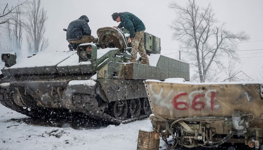 Hai người lính đang sửa chữa một chiếc xe chiến đấu bộ binh M2 Bradley tại địa điểm không được tiết lộ ở vùng Donetsk ngày 9/2. 
