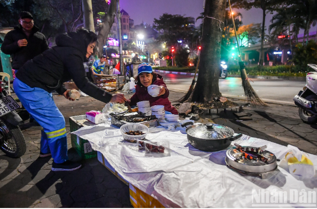 Gần 9 giờ tối, khi được tạm nghỉ, cả tổ mới quây quần với nhau bên vỉa hè. Lúc này, một mâm cơm tất niên đơn sơ được bày ra ngay bên vỉa hè vắng vẻ.