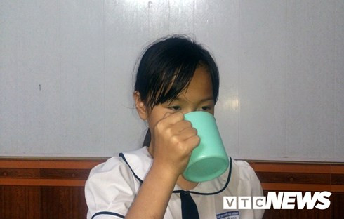 Bé Phương Anh cầm cái cốc ở nhà mô tả lại cái cốc tương tự em đã từng uống 1/2 nước giặt giẻ lau bảng ở lớp do cô giáo phạt.