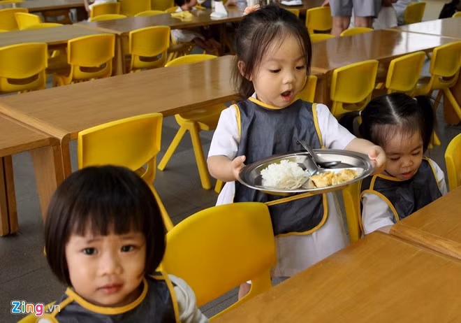 Những em lớn tự đi lấy khẩu phần ăn mang tới chỗ ngồi. Đây là một trong những bài học cho trẻ về kỹ năng tự phục vụ.