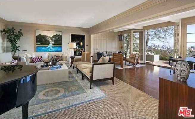 Phòng khách rộng rãi, sang trọng, ngập tràn ánh sáng tự nhiên. Những cánh cửa dẫn ra hiên nhà đón nắng cung cấp một tầm nhìn bao quát khung cảnh thành phố Los Angeles sống động, nhộn nhịp.