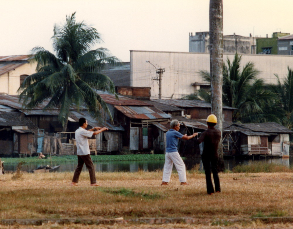 Người cao tuổi tập thái cực quyền trên bãi đất trống.