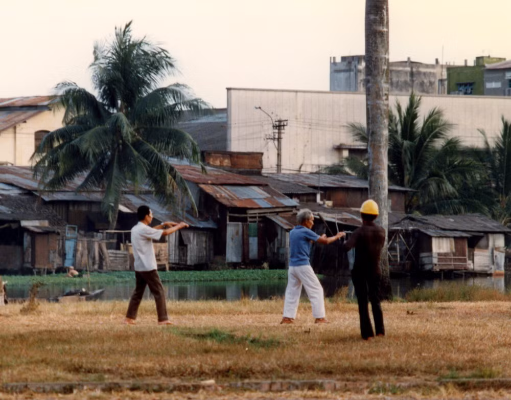 Người cao tuổi tập thái cực quyền trên bãi đất trống.