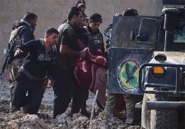 Các thành viên sư đoàn này đang mang một đồng đội bị thương vào trong xe trong cuộc giao tranh trong thành phố Mosul với tổ chức IS. Ảnh FNA