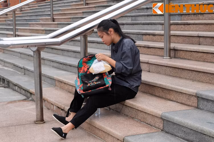 Một nữ sinh vừa tranh thủ ôn bài vừa chuẩn bị bánh mì lót dạ.