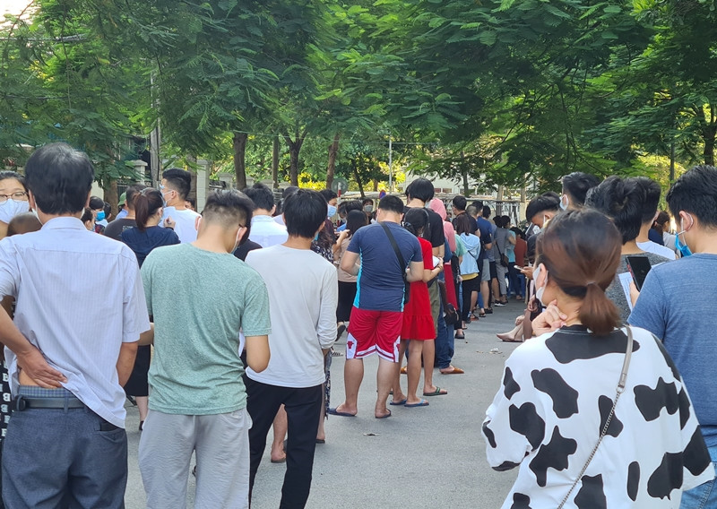 Dòng người xếp hàng dài từ cổng trạm y tế cho đến điểm giao với phố Đồng Me.