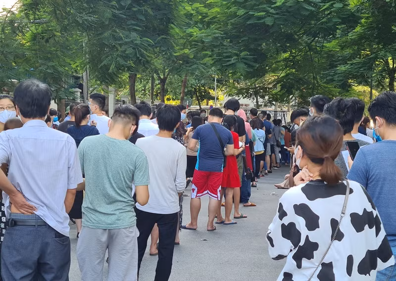 Dòng người xếp hàng dài từ cổng trạm y tế cho đến điểm giao với phố Đồng Me.