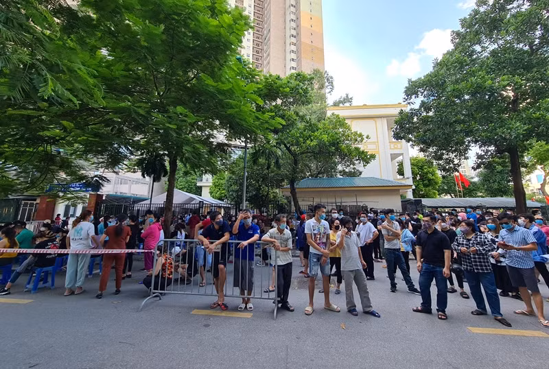 Trong khoảng thời gian chờ đến lượt tiêm, người dân dân đứng ở lòng đường trò chuyện, không đảm bảo giữ khoảng cách.