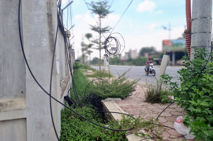 Đường dây điện, dây cáp viễn thông thòng lòng xuống vỉa hè đoạn đường.