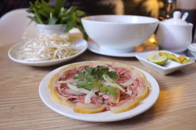  Phở thịt bê thui sống: Một phần phở đặc biệt này có một đĩa thịt bê thui còn sống và tô phở. Khi ăn, bạn sẽ phải thả miếng thịt sống vào bát phở bốc khói và nhâm nhi từng chút một. Ảnh: Món ngon Sài Gòn.