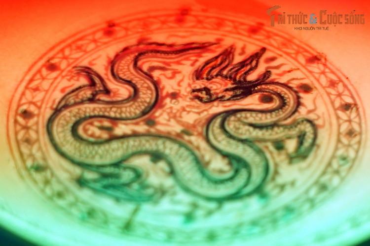 Đồ án hình rồng và văn mây trên chiếc đĩa được phác họa tinh tế bằng các nét vẽ xanh cobalt dưới men. Các bộ phận còn lại của con rồng được tô vẽ khéo léo bằng men đỏ, men xanh lá cây trên men nền, sau đó được phủ vàng thật lên các họa tiết trang trí.