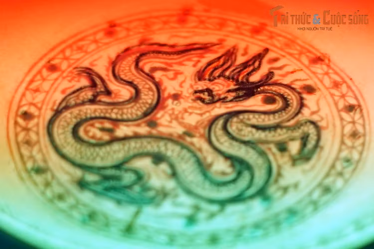 Đồ án hình rồng và văn mây trên chiếc đĩa được phác họa tinh tế bằng các nét vẽ xanh cobalt dưới men. Các bộ phận còn lại của con rồng được tô vẽ khéo léo bằng men đỏ, men xanh lá cây trên men nền, sau đó được phủ vàng thật lên các họa tiết trang trí.