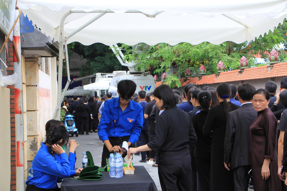Hàng dài người xếp chờ viếng và được các đoàn viên, thanh niên hỗ trợ nước, khăn giấy.