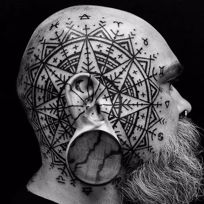 Xăm đầu hình học và đeo một chiếc khuyên tai khổng lồ khiến người đàn ông trong ảnh như người của hành tinh khác. Ảnh: Zonetattoo.