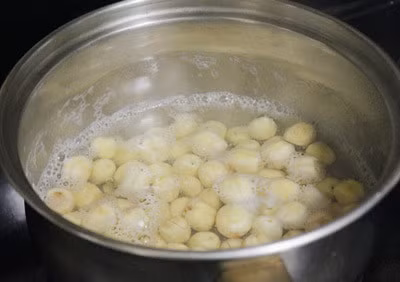 Hạt sen rửa sạch hạt, cho vào nồi ninh tới khi hạt sen mềm thì vớt ra. Tiếp đó, cho 170g đường phèn vào nồi nước nấu hạt sen nấu cho tan đường rồi đổ hạt sen vào đun tiếp tới khi đường ngấm vào từng hạt thì bắc ra để nguội, phần hạt sen vớt ra để riêng. Ảnh: Ngonhetsay.