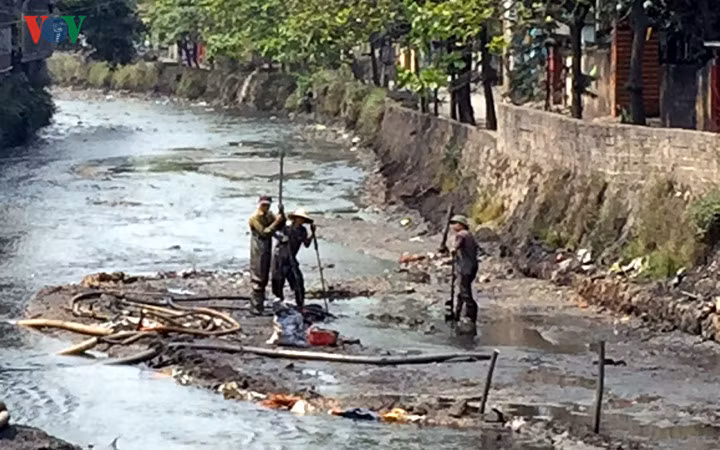 Để hút được than cám trôi phải có một nhóm người xuống dưới lòng sông để vét than và bùn vào miệng hút.