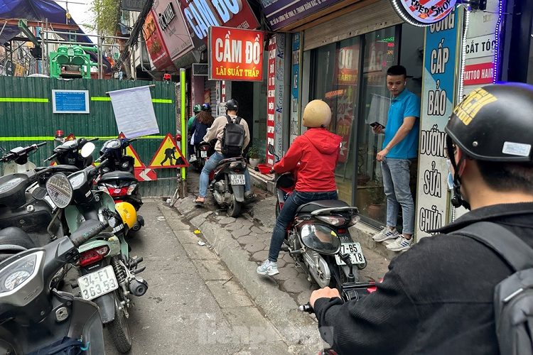 Người dân chỉ được hàng rào công trườngchừa lại một phần vỉa hè để vừa đi xe máy, vừa đi bộ, còn ô tô bị chiếm hết lòng đường.