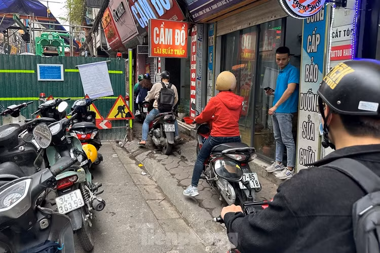 Người dân chỉ được hàng rào công trườngchừa lại một phần vỉa hè để vừa đi xe máy, vừa đi bộ, còn ô tô bị chiếm hết lòng đường.